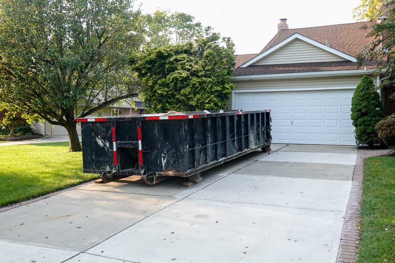 Black dumpster in a house's driveway